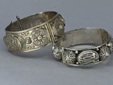 pair of silver bracelets with engraved designs on them on a gray surface