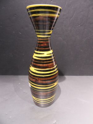 un vase rayé posé sur une table devant un mur gris