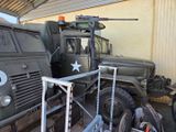 two army trucks parked next to each other in a garage