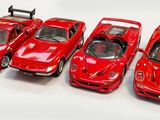Quatre petites voitures rouges sont alignées en rang sur une surface blanche