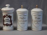 three white and gold canisters are lined up against a gray background