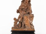 an antique bronze statue of a woman with a child and a dog