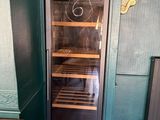 a wine cooler in the corner of a room with green walls