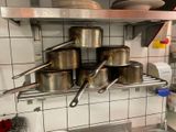de nombreuses casseroles et poêles qui se trouvent sur une étagère dans la cuisine