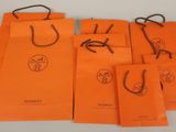 a group of orange paper bags with black string handles