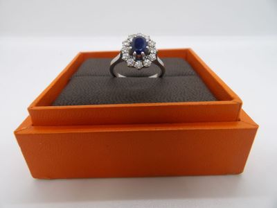 une photo d'une bague sertie d'un diamant et d'un saphir, présentée dans un écrin orange