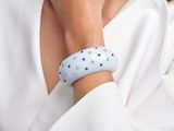 La femme porte une chemise blanche et un bracelet bleu.