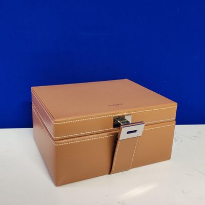 a brown leather box with a lock on top of a table