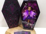 l'image d'une poupée vêtue d'une robe violette et aux cheveux violets, dans une boîte noire