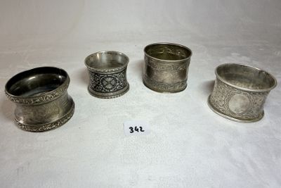 quatre tasses en argent sont alignées sur une surface blanche