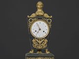 une horloge sur laquelle trône une statue, posée sur une table