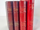 four red books are lined up in a row on a white surface