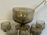un saladier en verre avec une cuillère et des verres posés sur une table