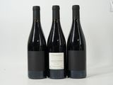 trois bouteilles de vin rouge sont posées sur une surface blanche