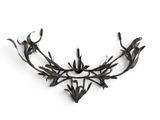 black metal wall sculpture of leaves and branches on a white background