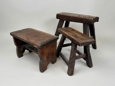 deux petits tabourets en bois placés l'un à côté de l'autre sur une surface blanche
