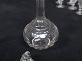a glass bottle with a stopper next to a group of wine glasses