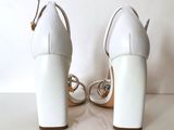 pair of white high heeled shoes sitting on top of a white table
