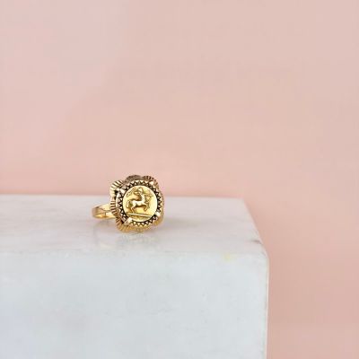 une bague en or portant la lettre « e », posée sur un bloc de marbre