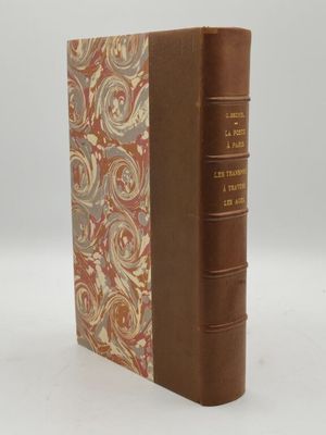 un vieux livre à la couverture marron posé sur une table blanche
