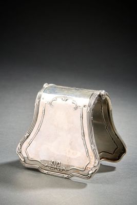 an antique silver purse on a grey surface with a black background
