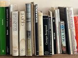 many books on a shelf with a clock above them