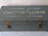 an old wooden box with a label on it sitting on a white surface
