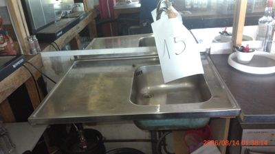 a metal sink with a sign on it in a kitchen
