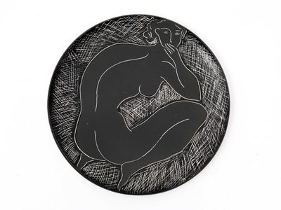 une assiette noire sur laquelle est représentée une femme