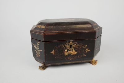 an old black and gold box sitting on top of a white surface