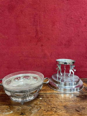 two silver candlesticks and a bowl on a wooden table