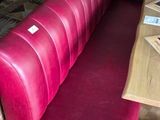 a red bench in the middle of a restaurant with wooden tables