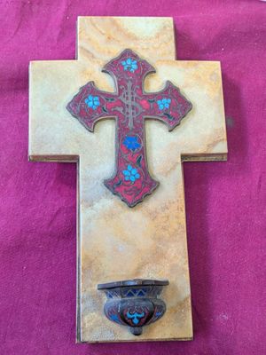 une croix ornée d'une fleur bleue et un bol posé par terre