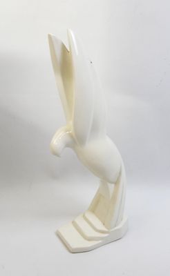 white ceramic sculpture of a bird on a stand on a white background
