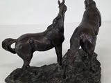 statue of two horses standing on a rock on a white surface