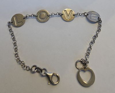 bracelet à chaîne en argent orné de breloques, posé sur un fond blanc