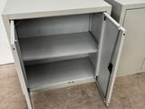 a white metal cabinet with open doors and shelves in a room