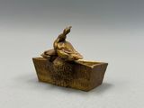 une statue en bronze représentant un canard perché sur un bloc de bois