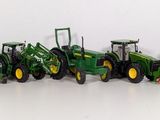 many toy tractors lined up in a row on a white surface