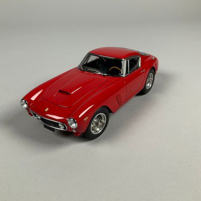 a red toy car that is sitting on a white surface