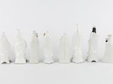 seven figurines of people dressed in white on a white background