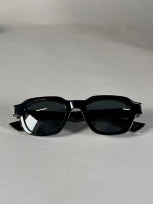 des lunettes de soleil noires ornées de pointes sur les branches, posées sur une table