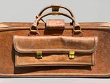 une valise marron posée sur une table, munie d'une poignée