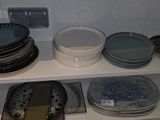 many plates and bowls on the shelves in the kitchen