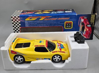 une petite voiture jaune dans une boîte blanche, avec une boîte à carreaux noirs et blancs derrière