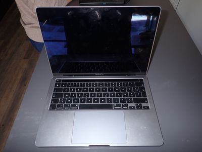 a laptop computer sitting on a table with a person in the background