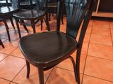 de nombreuses chaises noires dans un restaurant, avec une table en arrière-plan