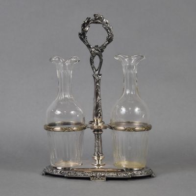 two glass vases and a silver plate with a handle on a stand