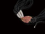 un gros plan sur un collier de perles noires orné de pierres roses et blanches