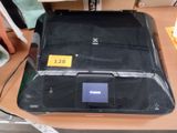 une imprimante noire posée sur une table, sur laquelle est collé un autocollant jaune